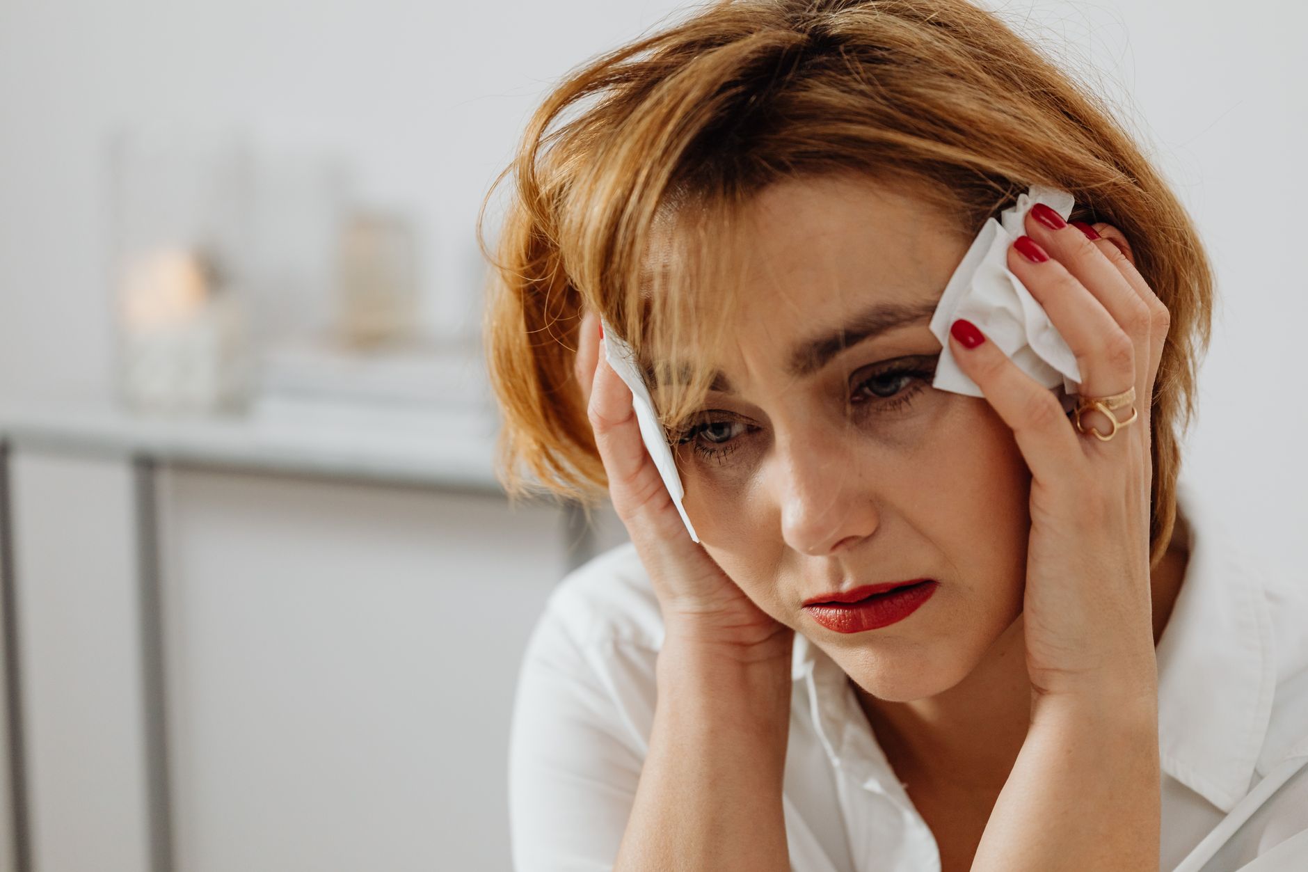 Close-up of a woman in distress holding tissues, expressing emotional sadness.