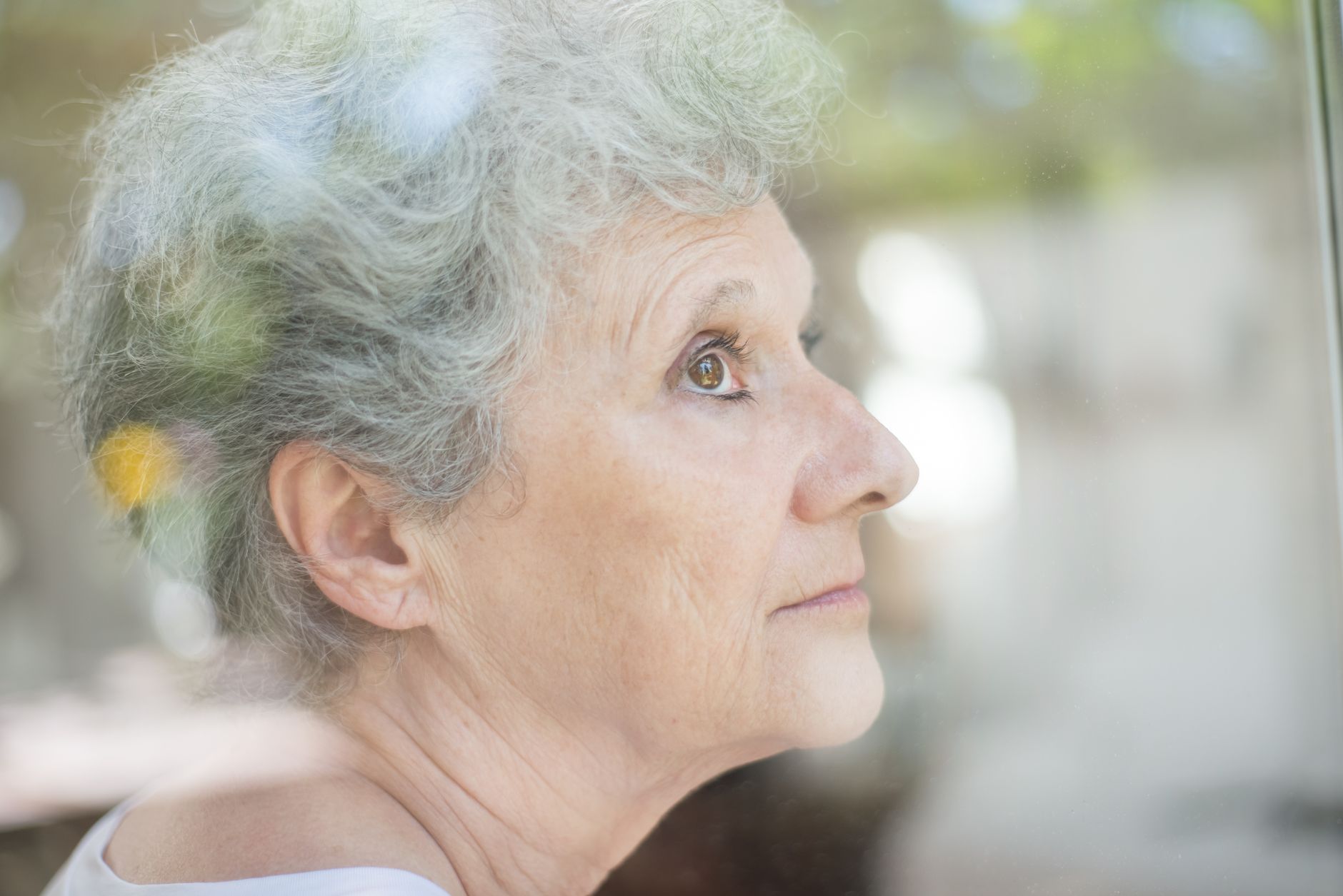 Thoughtful mature woman looking out window calmly