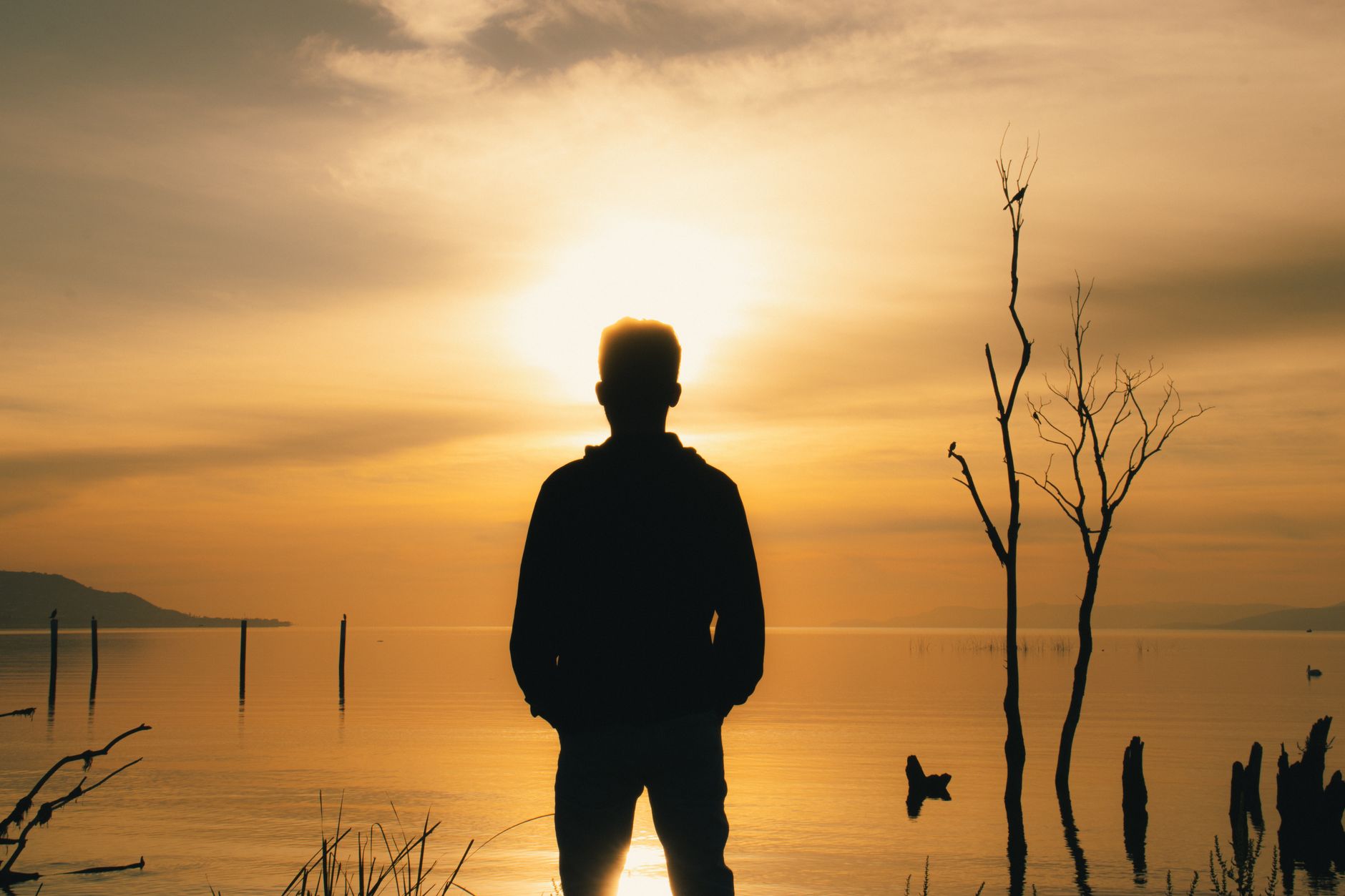 Silhouette of a man standing by Jocotepec Lake at sunset, Mexico