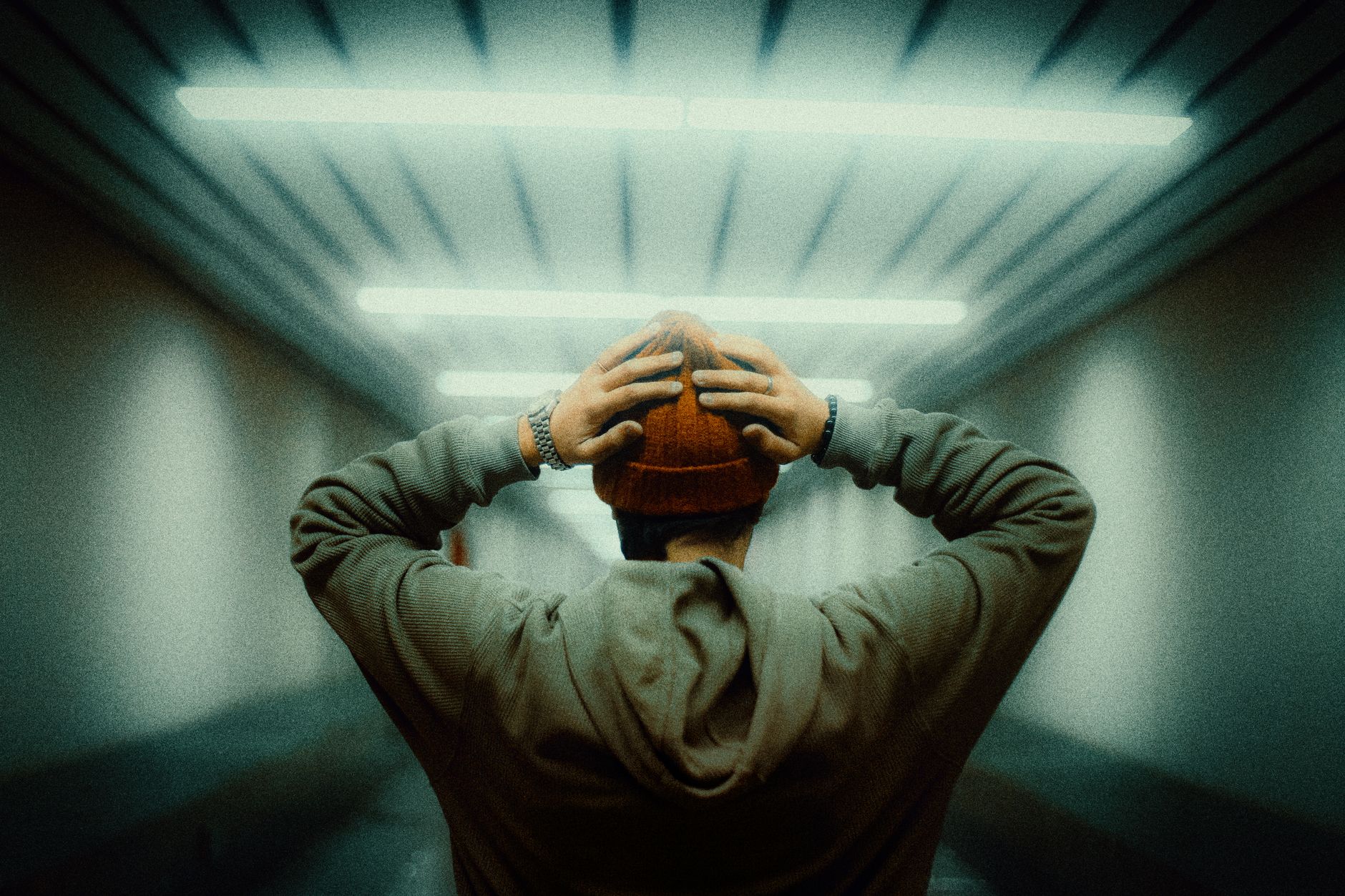 A person stands alone in a tunnel with hands on head, exuding a sense of contemplation and introspection.