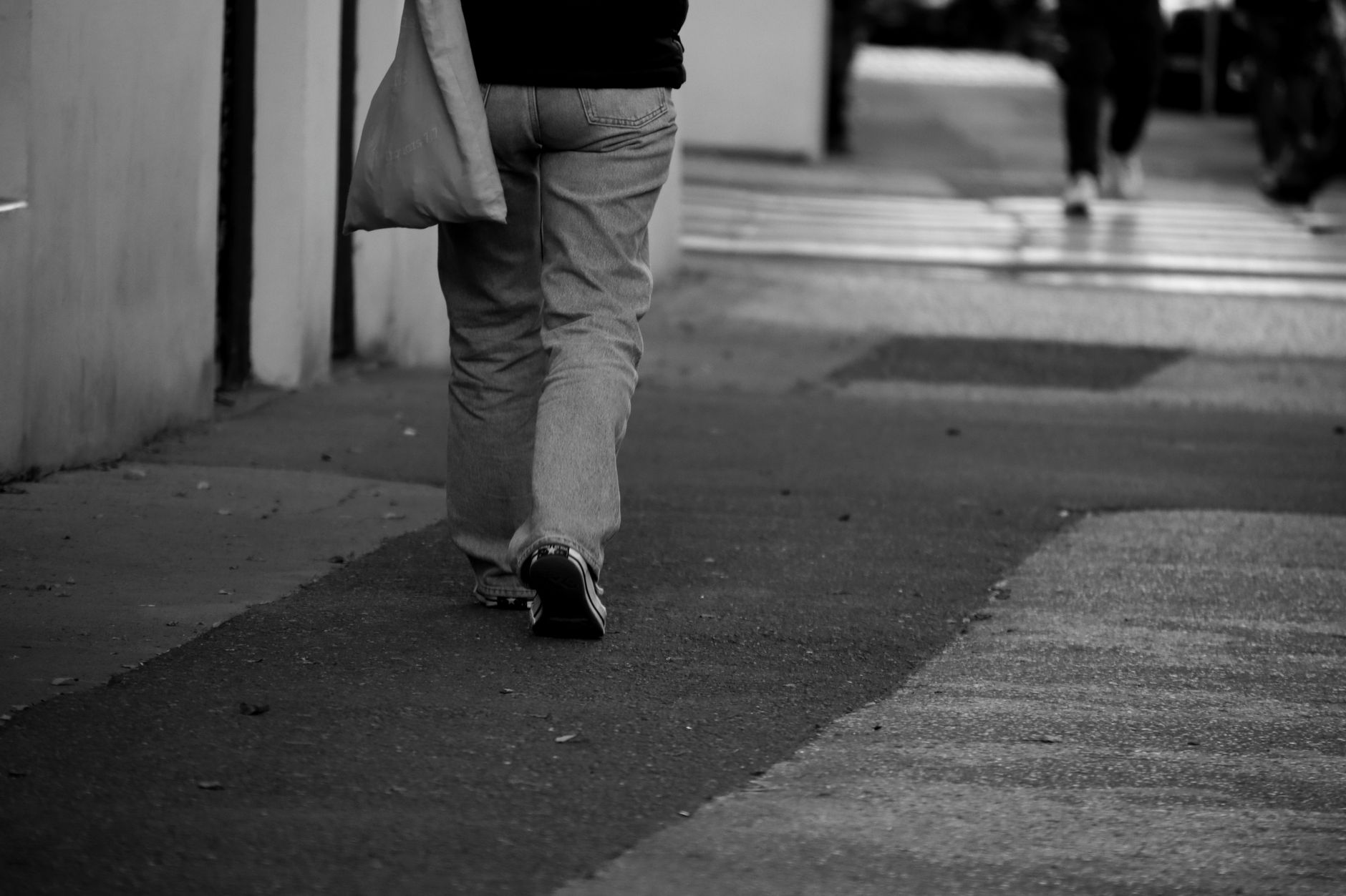 A monochrome photo of a person walking on a city sidewalk in Czechia.